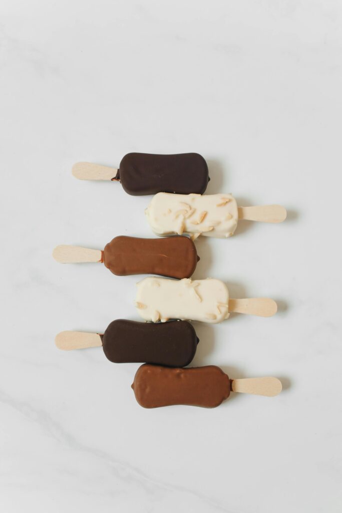 An artistic arrangement of chocolate and vanilla ice cream bars on a white marble surface.